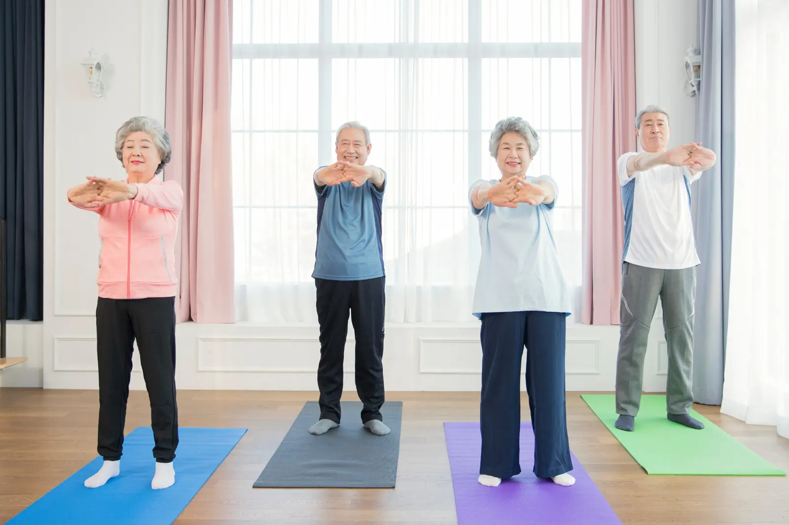 Four older adults stretching together on yoga mats during a gentle healthy aging exercise class